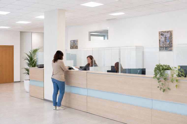 Una cittadina attende seduta in una sala d'attesa luminosa, prima del suo appuntamento allo sportello.